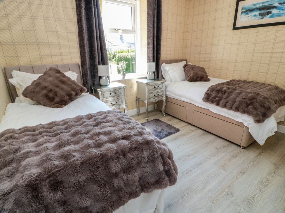 A bedroom with two beds and a nightstand at Waterside Lodge in Annan