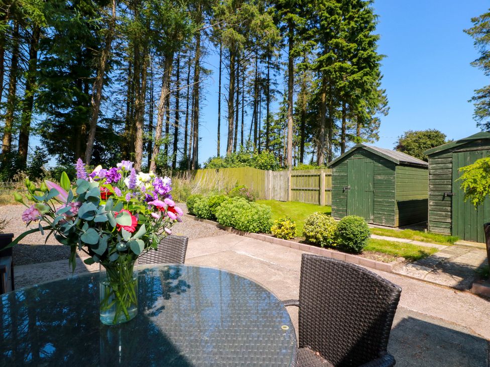 A garden with a table and flowers at Waterside Lodge in Annan