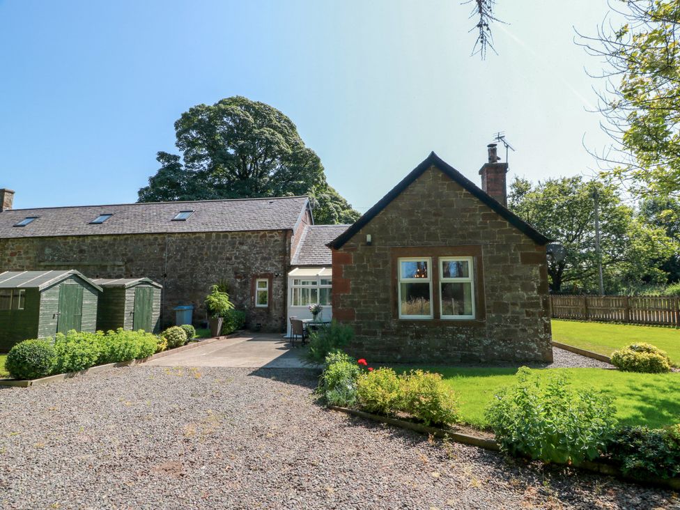 An outdoor view of a house with trees and garden at Waterside Lodge Annan