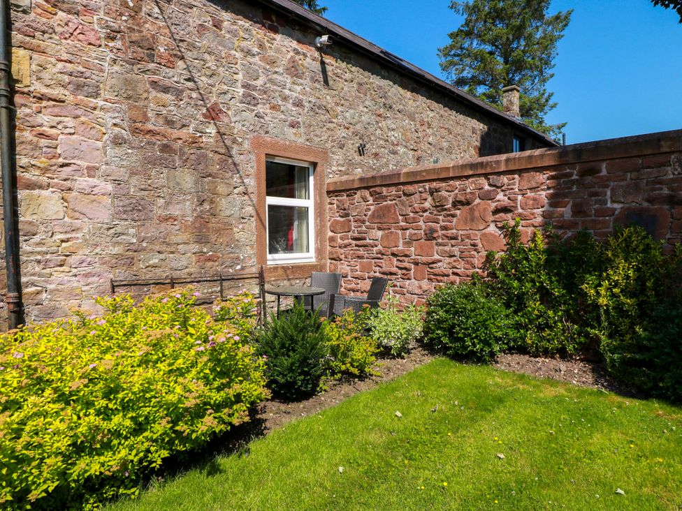 A garden area with a stone wall and seating at Waterside Lodge in Annan