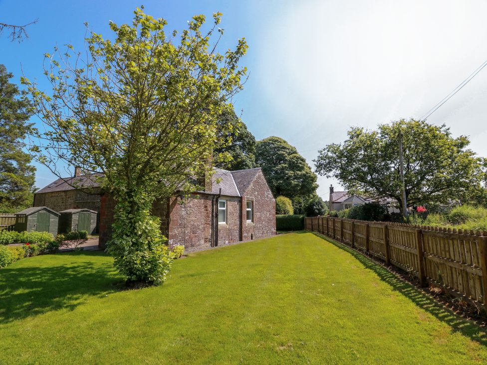 A garden with a house and trees at Waterside Lodge Annan