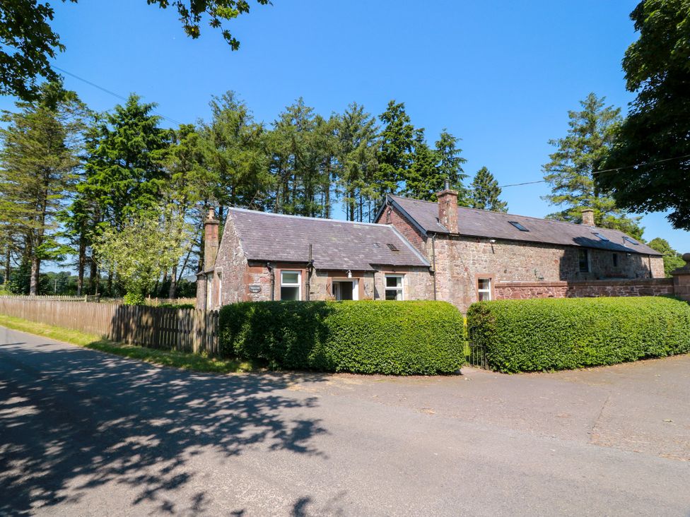 A house on the corner of a road with trees and shrubbery at Waterside Lodge Annan