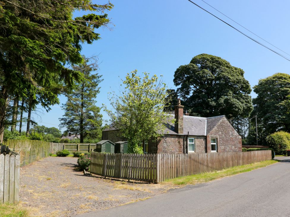 A house with a fence and trees at Waterside Lodge in Annan