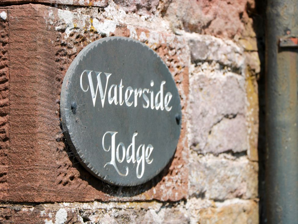 A sign reading Waterside Lodge on a stone wall at Waterside Lodge Annan