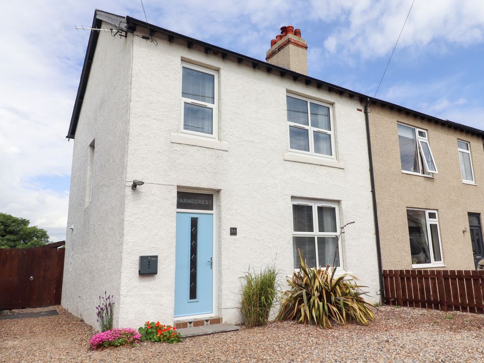A house exterior with a blue door and plants at Farnecrest in Seahouses