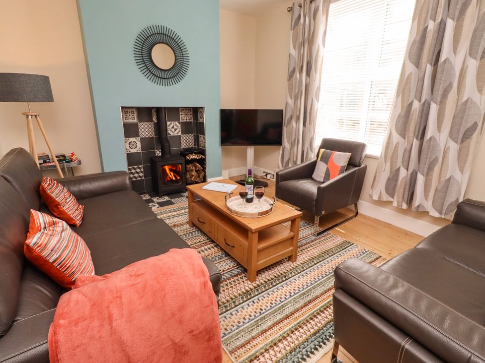 A living room with a sofa, armchair, coffee table and fireplace at Farnecrest in Seahouses