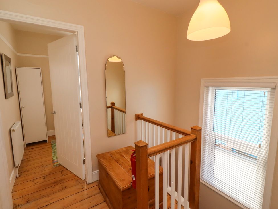 A hallway with a mirror and wooden chest at Farnecrest in Seahouses