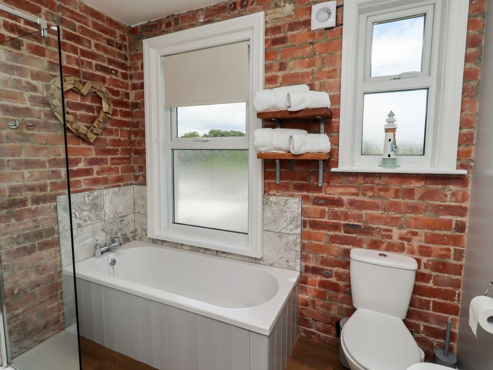 A bathroom with a bath tub and shower at Farnecrest in Seahouses