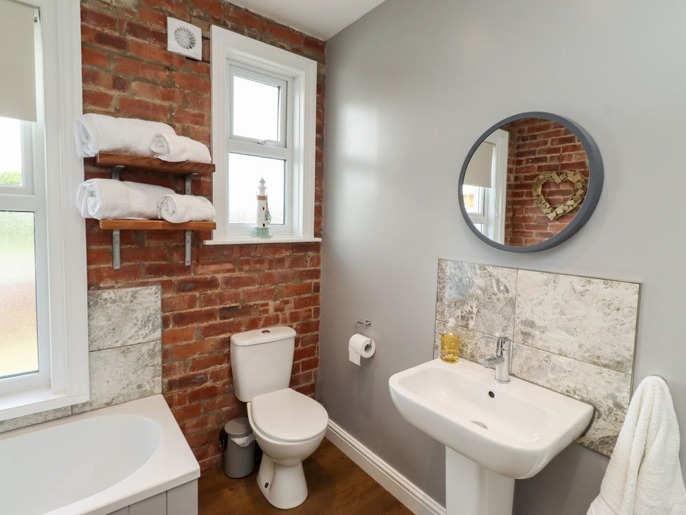 A bathroom with a bathtub, toilet, sink, and towels at Farnecrest in Seahouses