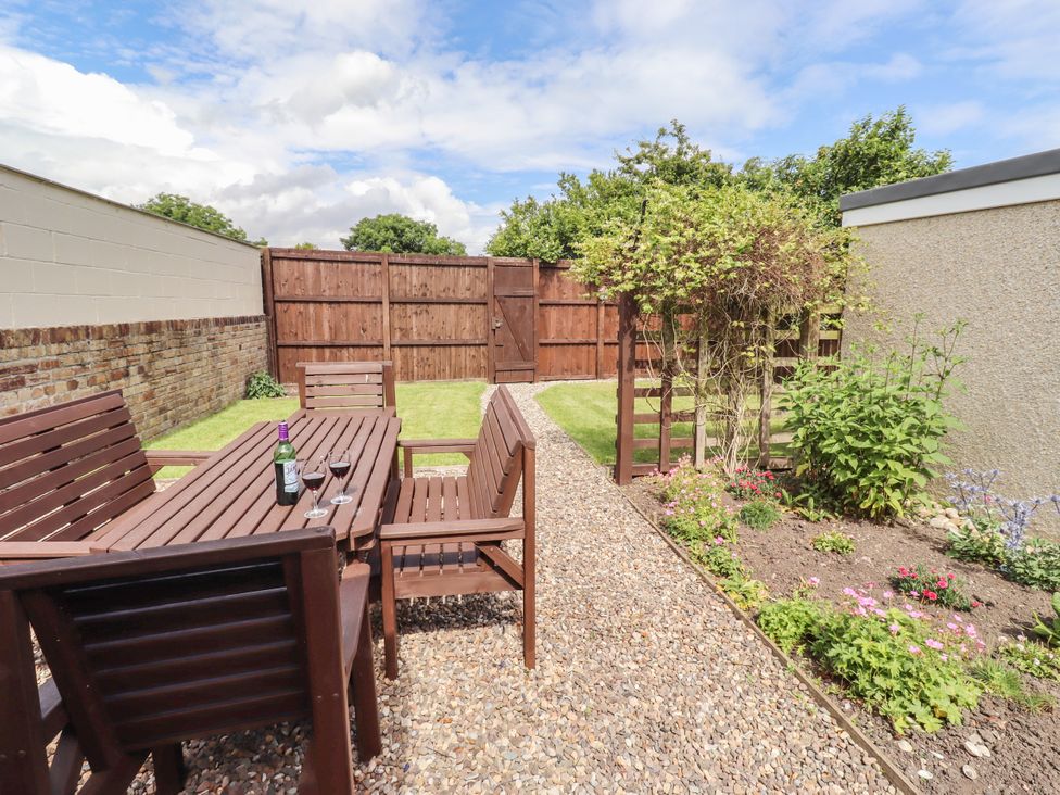A garden with a wooden table and chairs at Farnecrest in Seahouses