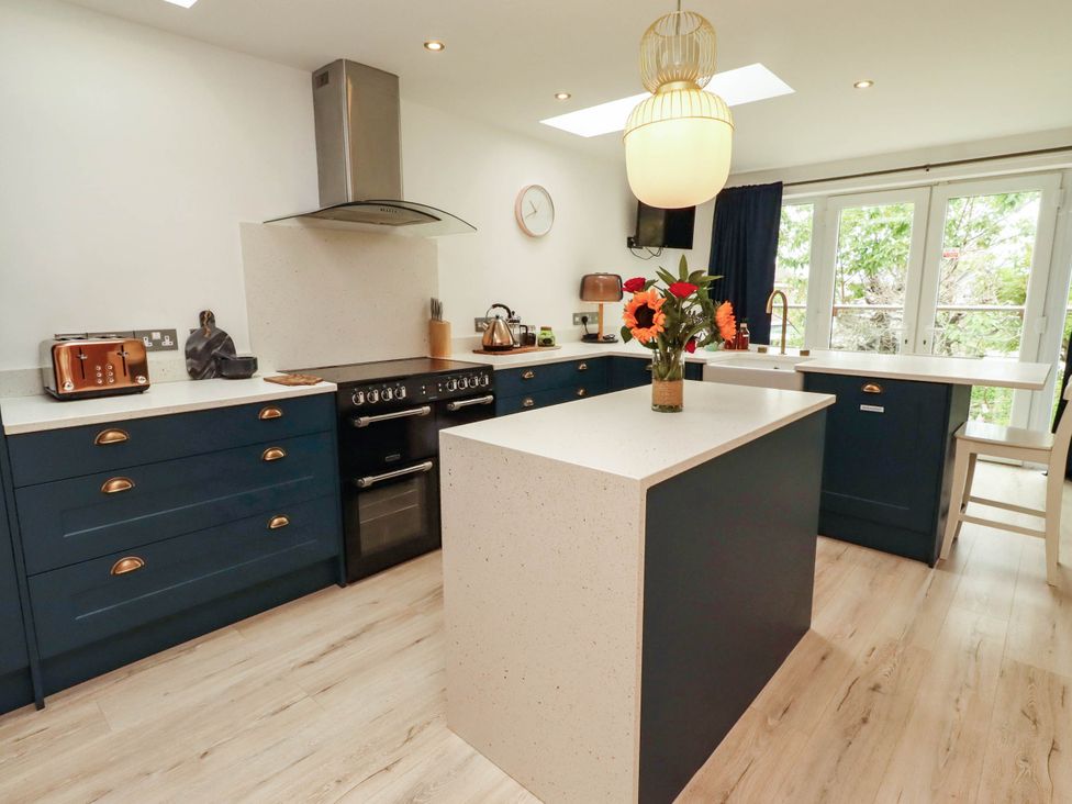 A kitchen with an island, oven, and flowers at Alma House in Seahouses