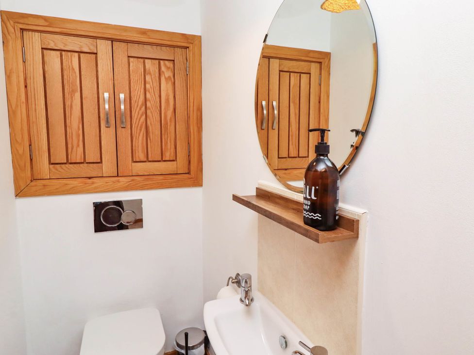 A bathroom with a toilet, mirror, and hand soap dispenser at Alma House in Seahouses