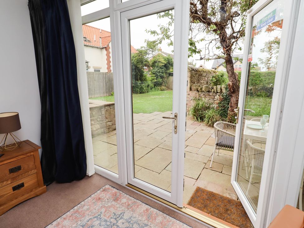 A conservatory with a view of a garden at Alma House Seahouses