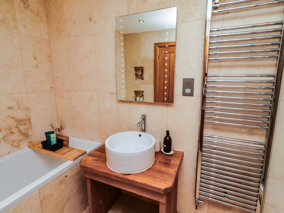 A bathroom with a bathtub and sink at Alma House Seahouses