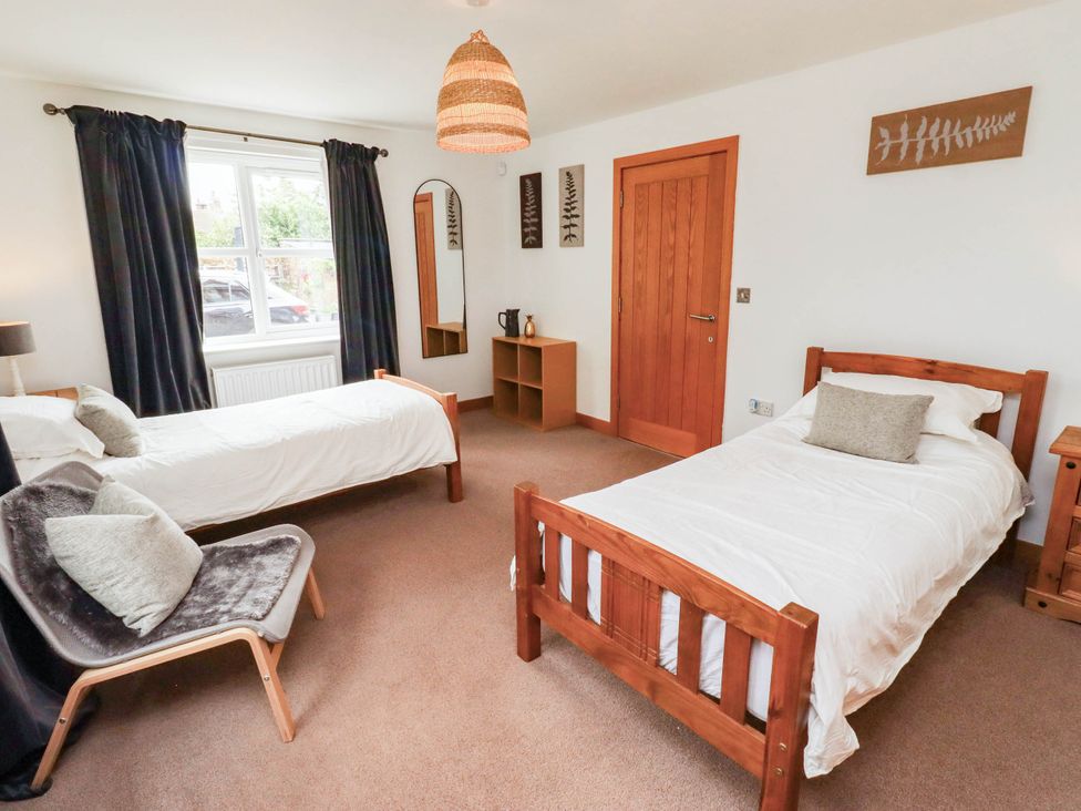 A bedroom with two beds and a chair at Alma House in Seahouses