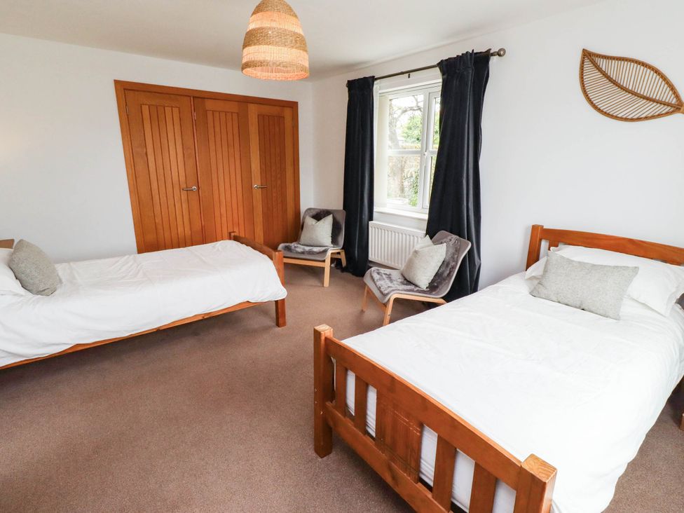 A bedroom with two beds and a wardrobe at Alma House in Seahouses
