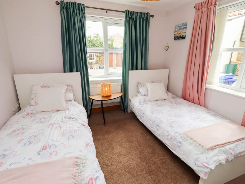 A bedroom with two beds and a bedside table at Alma House in Seahouses