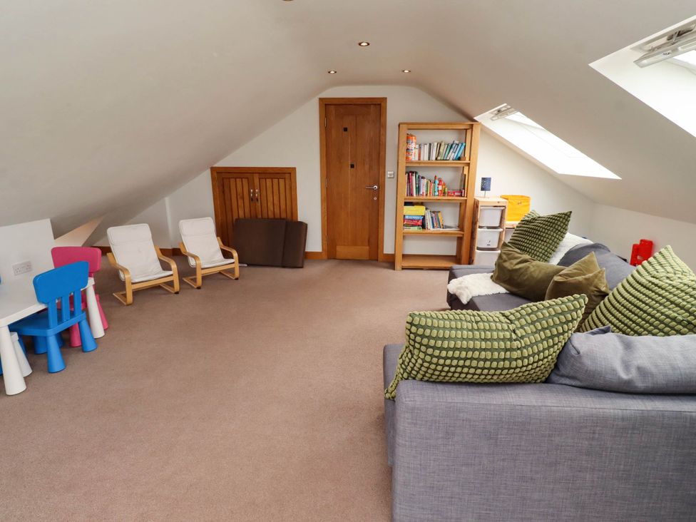 A loft space with a sofa and children's furniture at Alma House in Seahouses