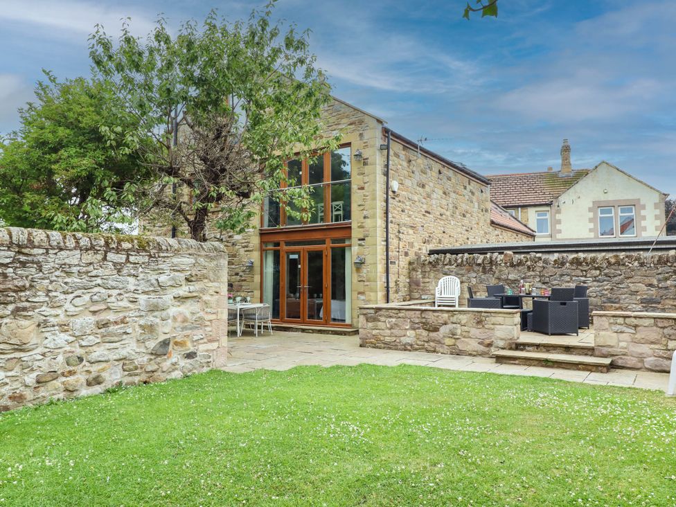 A patio area with seating and lawn at Alma House in Seahouses