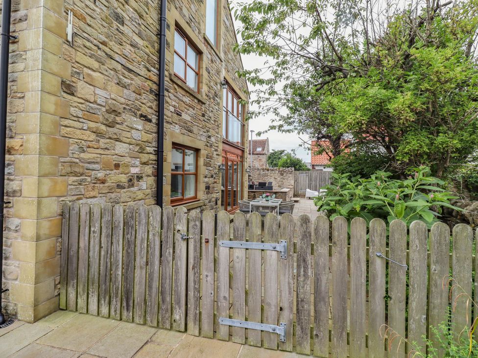 An outdoor area with a stone wall and wooden fence at Alma House in Seahouses