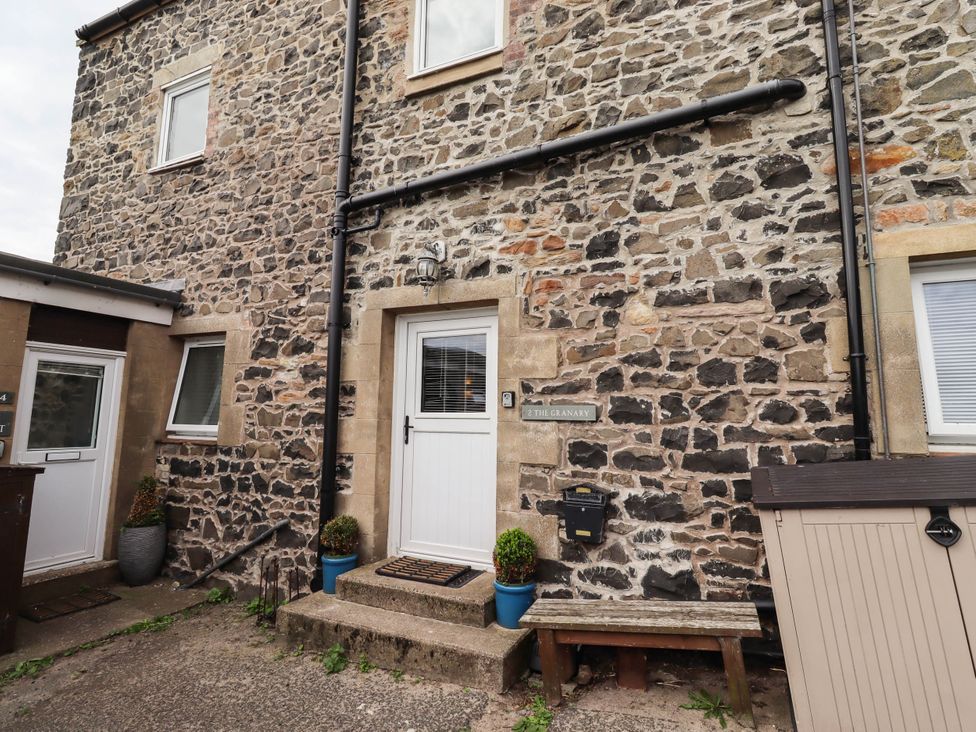 An outdoor view of a stone wall with a door and window at The Granary