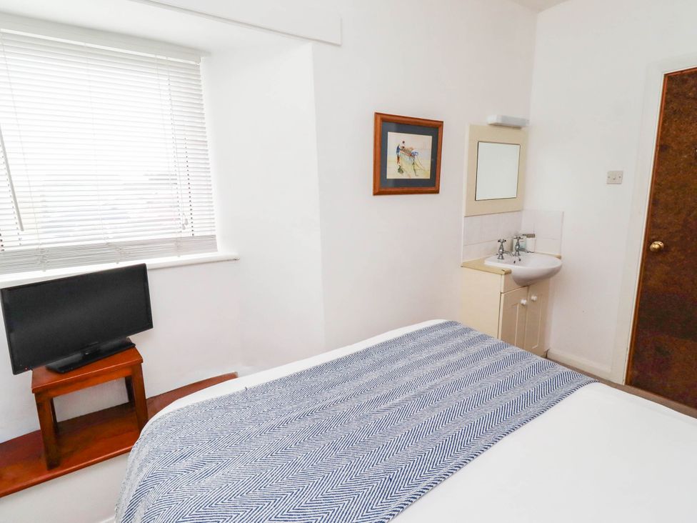 A bedroom with a bed, television, and sink at Spinnaker