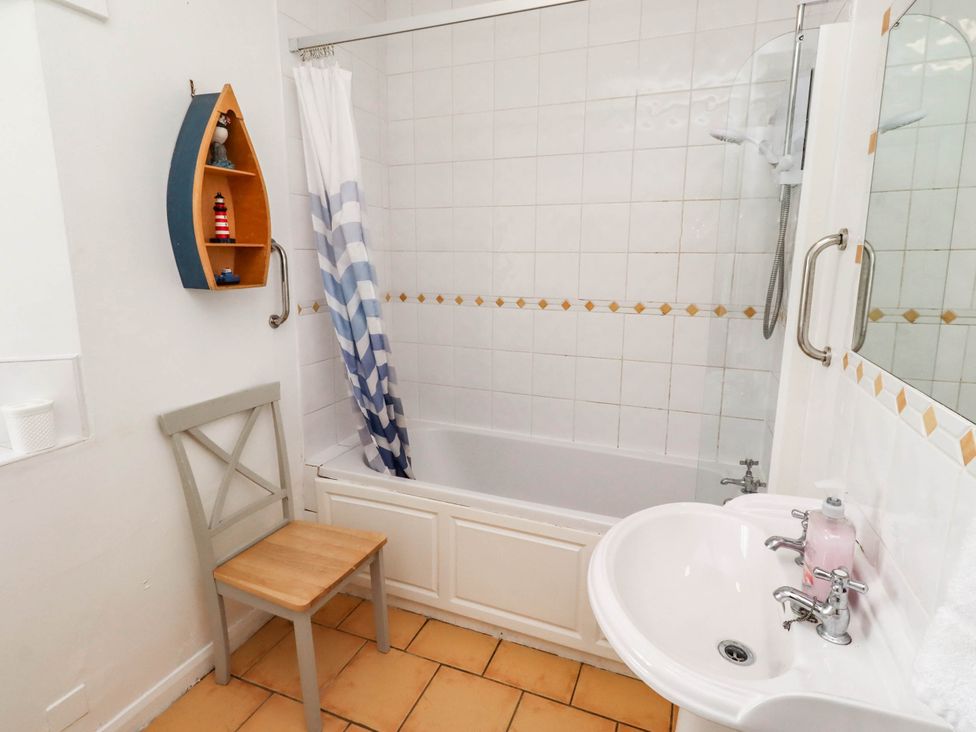 A bathroom with a bathtub, sink and chair at Spinnaker