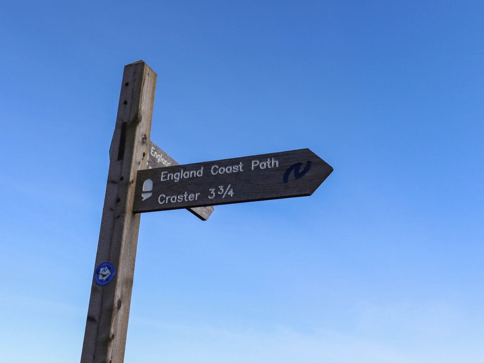 A signpost indicating the England Coast Path and Craster 3¾ miles