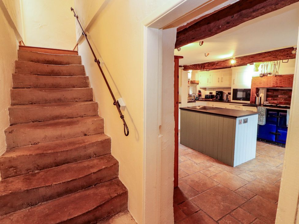 Stairs leading to a kitchen with an island and cabinets at Claybottom Farm near Hesket Newmarket