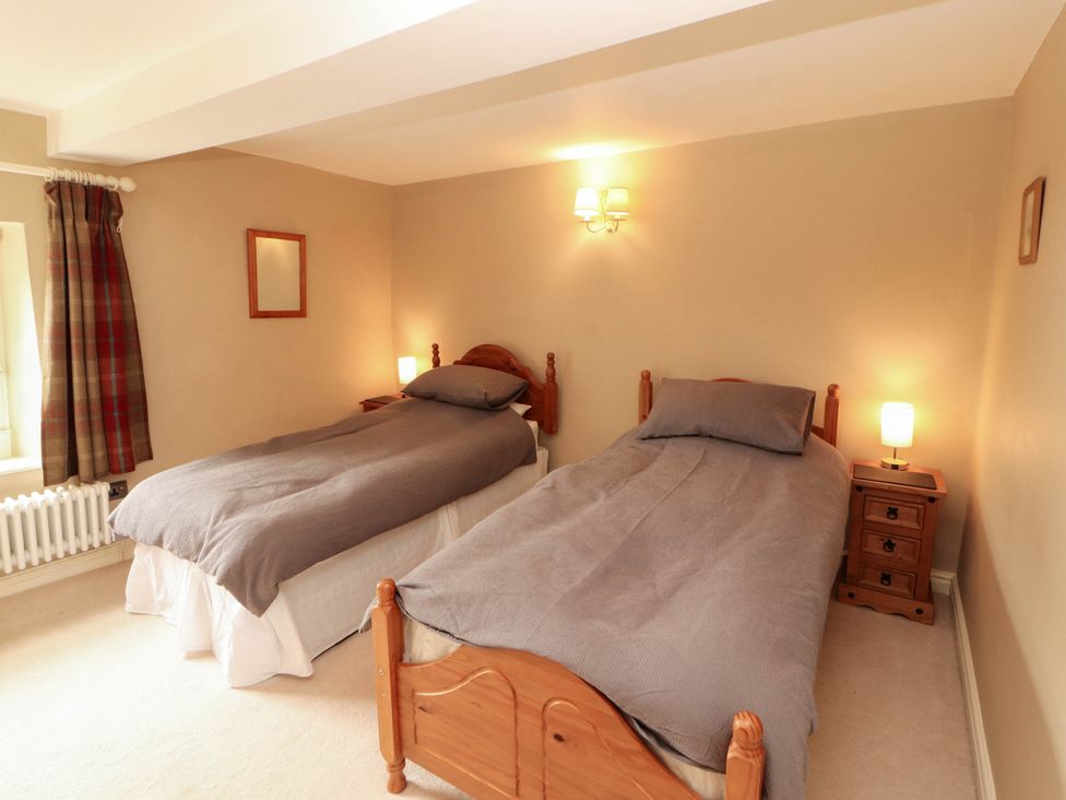 A bedroom with two single beds and a bedside table at Claybottom Farm near Hesket Newmarket