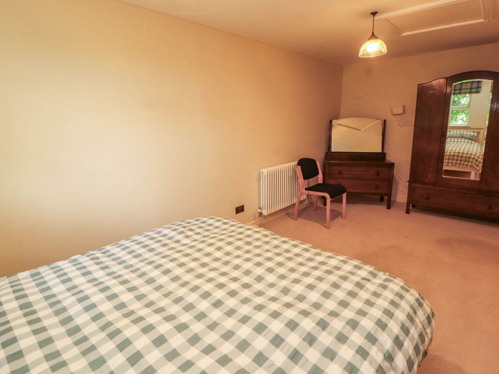 A bedroom with a bed, chair, and wardrobe at Claybottom Farm near Hesket Newmarket