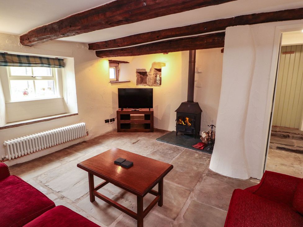 A living room with a wood stove and television at Claybottom Farm in Hesket Newmarket