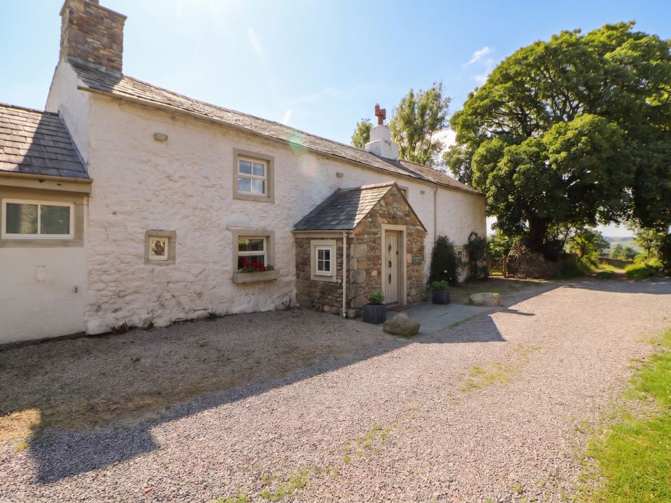An exterior view of a house with a gravel area and plants at Claybottom Farm in Hesket Newmarket