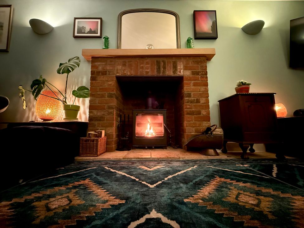 A living room with a fireplace and a rug at Fables Cottage in Otley, Suffolk