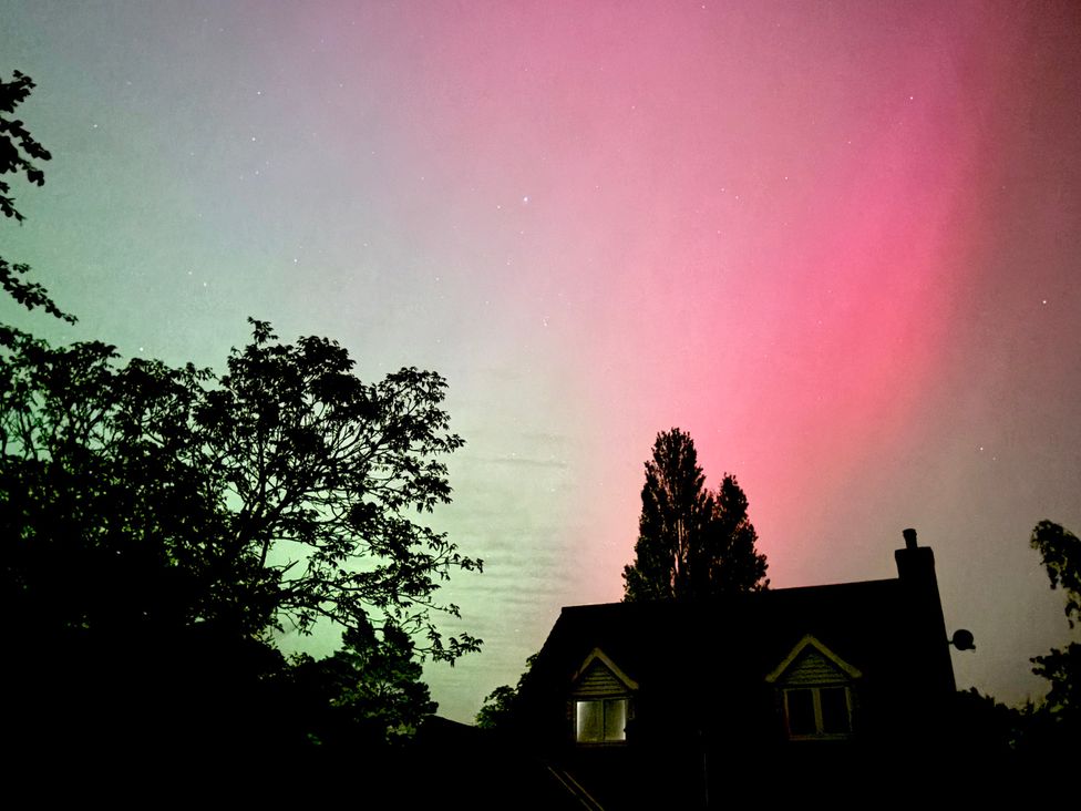 A sky with aurora colors over a house at Fables Cottage, Otley, Suffolk
