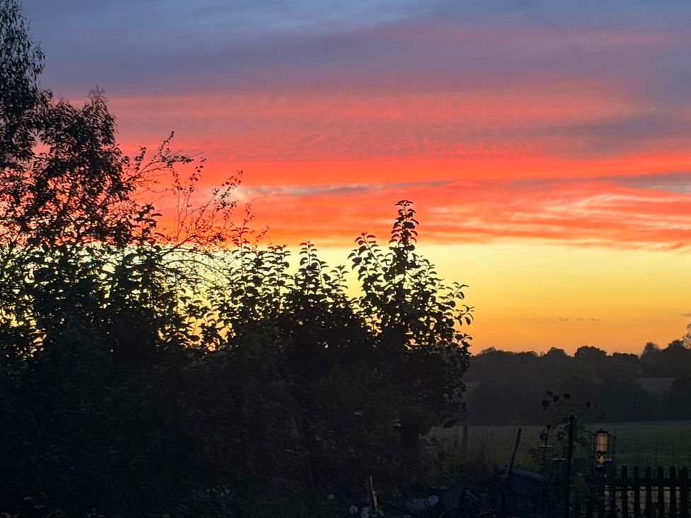 A sunset view with trees in a garden at Fables Cottage in Otley, Suffolk