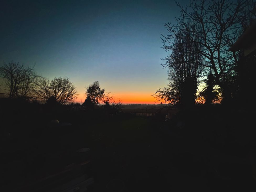 A sunset view with trees in the foreground at Fables Cottage Otley, Suffolk