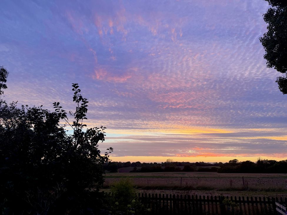 A sunset view with clouds and silhouettes of trees at Fables Cottage Otley, Suffolk