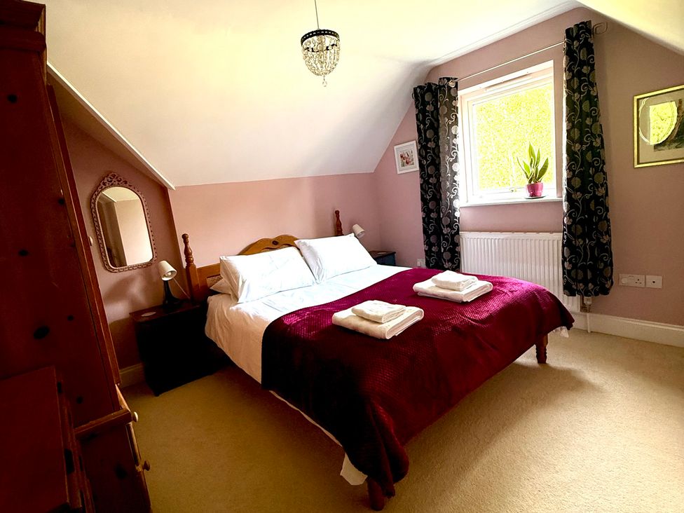 A bedroom with a bed and chair at Fables Cottage in Otley, Suffolk