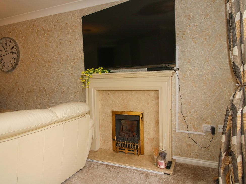 A living room with a television mounted above a fireplace at 18 Hengrave Meadow, Telford