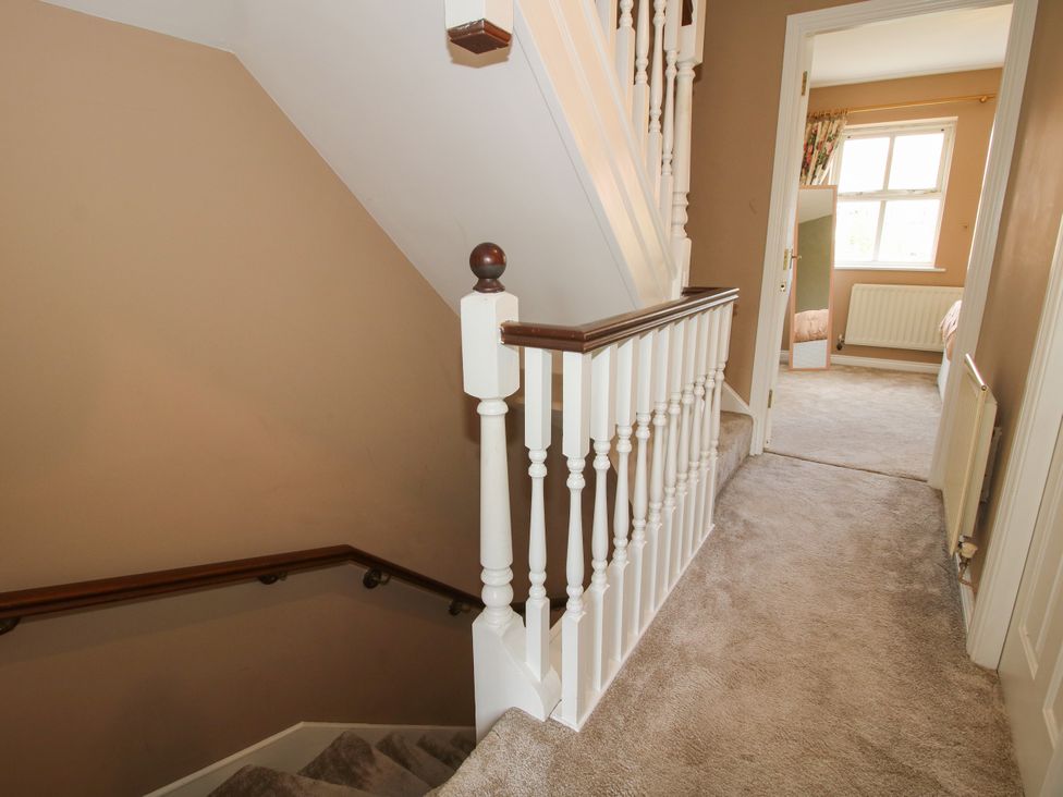 A staircase with a railing and a door leading to a room at 18 Hengrave Meadow Telford