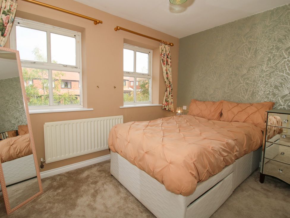 A bedroom with a bed, mirror, and windows at 18 Hengrave Meadow Telford