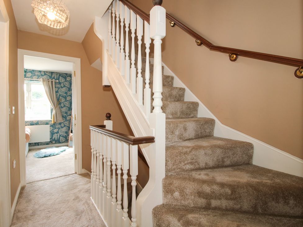 A hallway with a staircase and door at 18 Hengrave Meadow in Telford