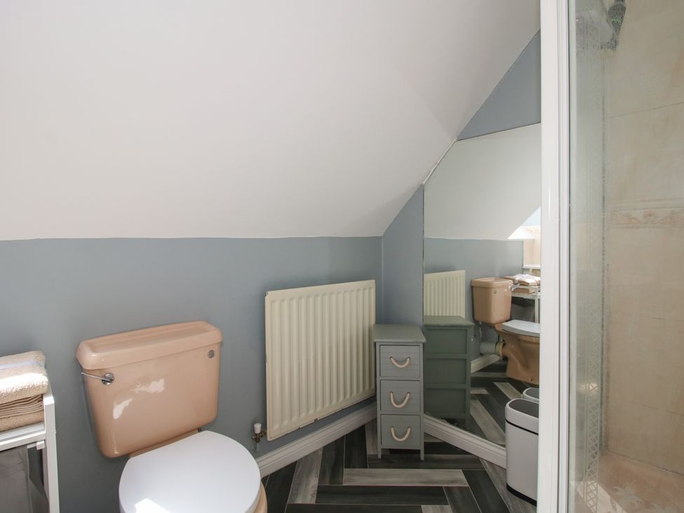 A bathroom with a toilet, sink, cabinet, mirror, and shower at 18 Hengrave Meadow Telford