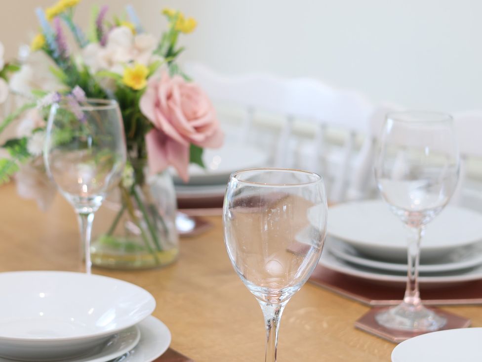 A dining room table set with wine glasses and plates at The Cosy Haven in Malton