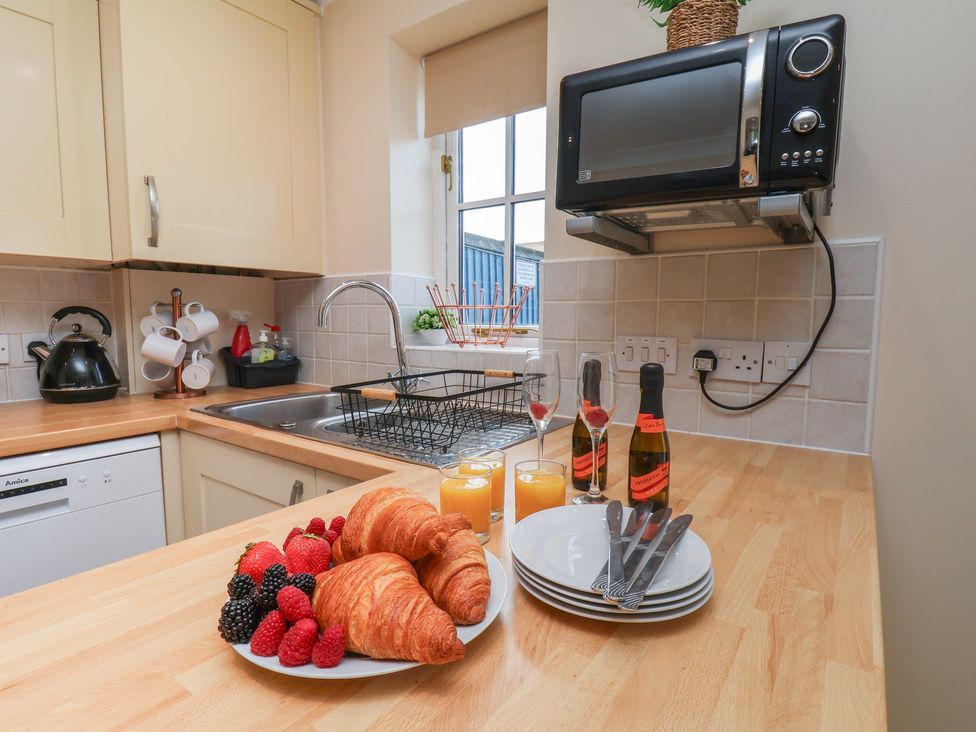A kitchen with a sink, microwave, and food items at The Cosy Haven in Malton