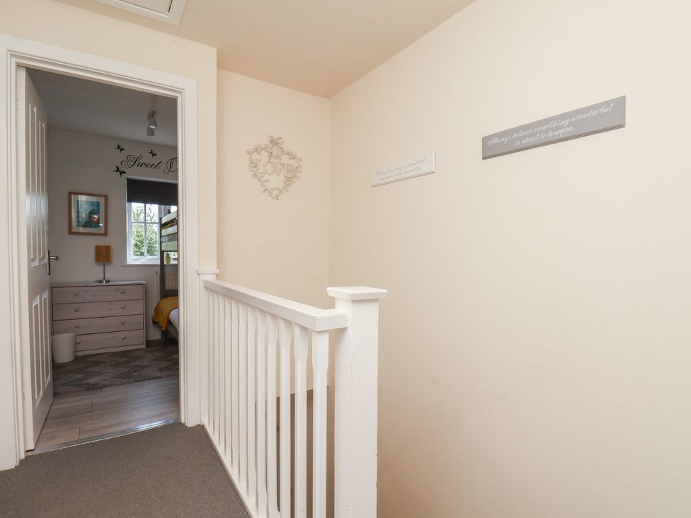 A hallway with a staircase leading to a room with a bed and window at The Cosy Haven in Malton