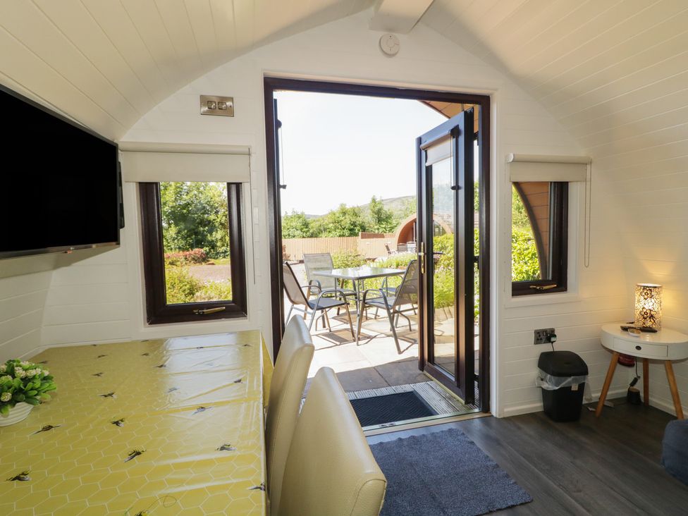 A living room with a dining table and door leading to outdoor seating at Gortin Glen Glamping Pod 3 in Omagh