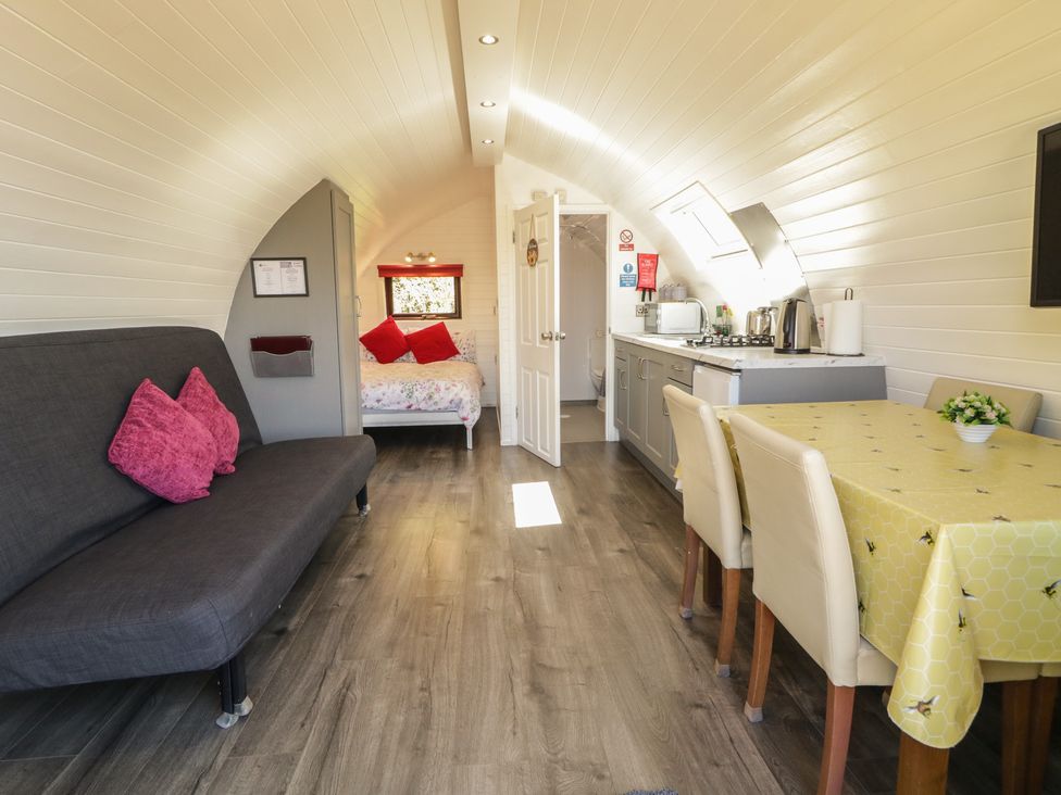 A living room with a sofa, table, and kitchen unit at Gortin Glen Glamping Pod 3 in Omagh