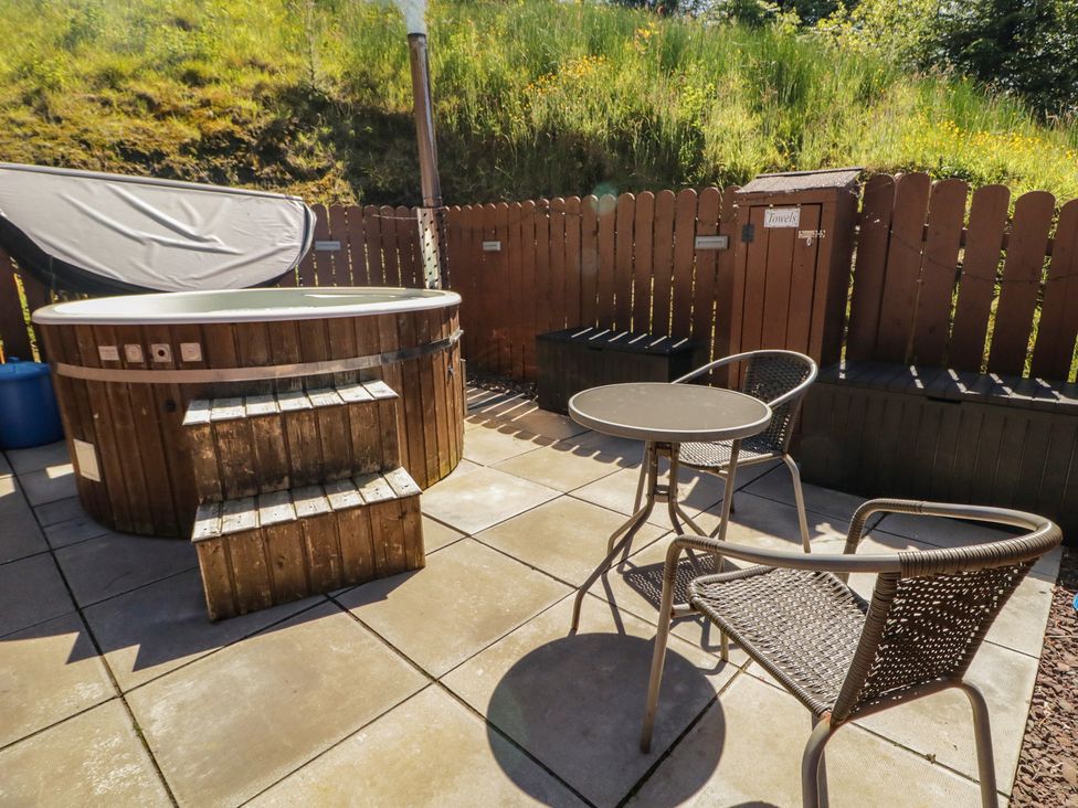 An outdoor area with a hot tub, chairs, and a table at Gortin Glen Glamping Pod 3 in Omagh